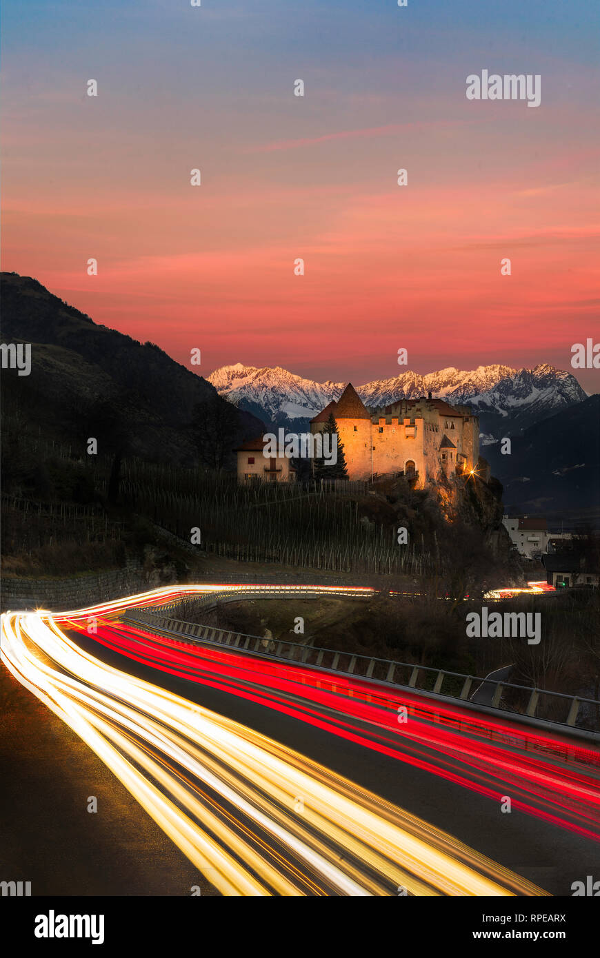 Light Trails sur route en passant Château vers les montagnes du Tyrol du Sud - sunset/alpine glow Banque D'Images