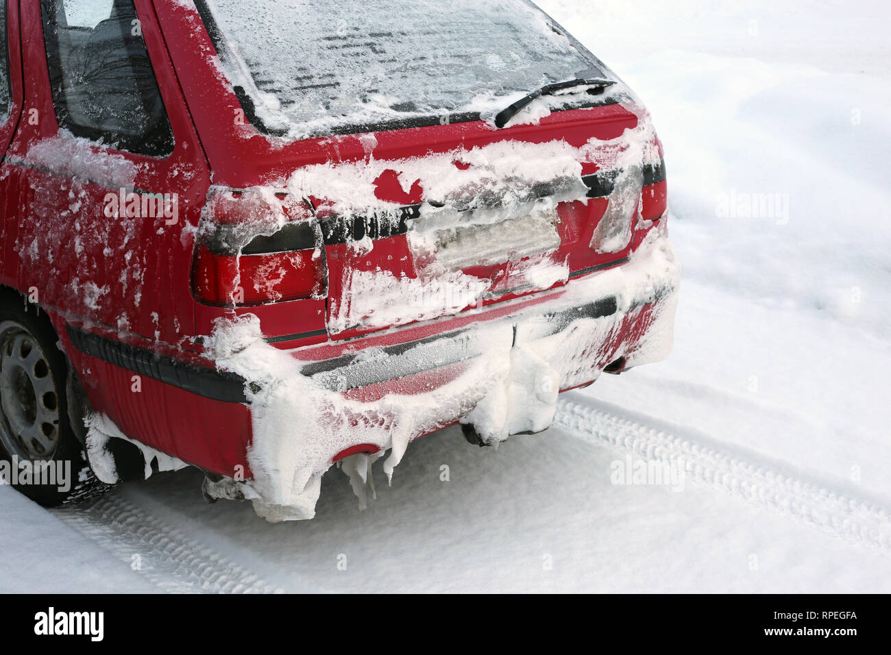 L'hiver en Europe. Vieille voiture rouge dans un parking à côté d'une forêt couverte de neige. Il y a beaucoup de nature neige autour de la voiture. Photo de jour. Banque D'Images