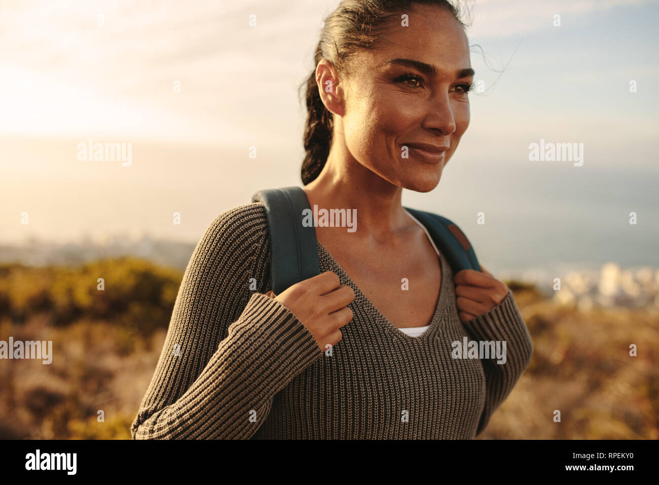 Femme marche sur un chemin de pays avec un sac à dos. Woman wearing sweater et sac à dos sur une randonnée. Banque D'Images