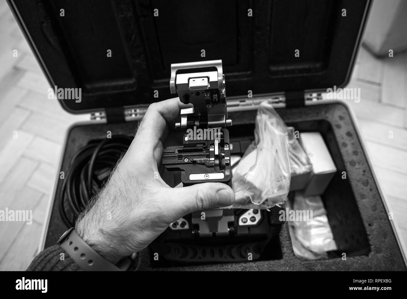 POV Technicien en fibre optique de haute précision cleaver pour couper la fibre optique FTTH très précisément au cours de la maison et le bureau moderne - fournisseur de services internet à l'aide de l'outil de haute précision - noir et blanc Banque D'Images