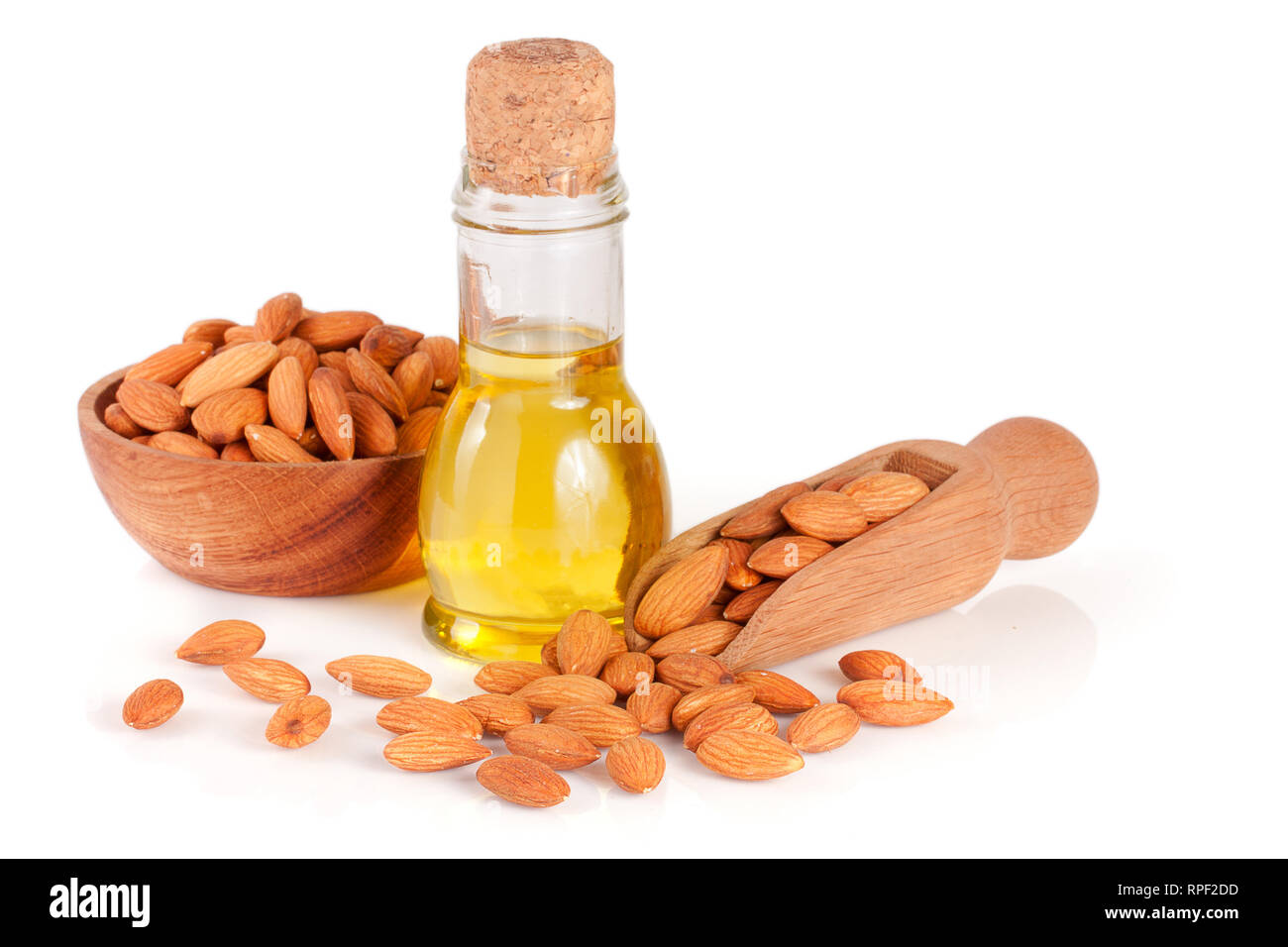 Bouteille d'huile d'amandes et d'amandes dans un bol en bois et scoop isolé sur fond blanc Banque D'Images