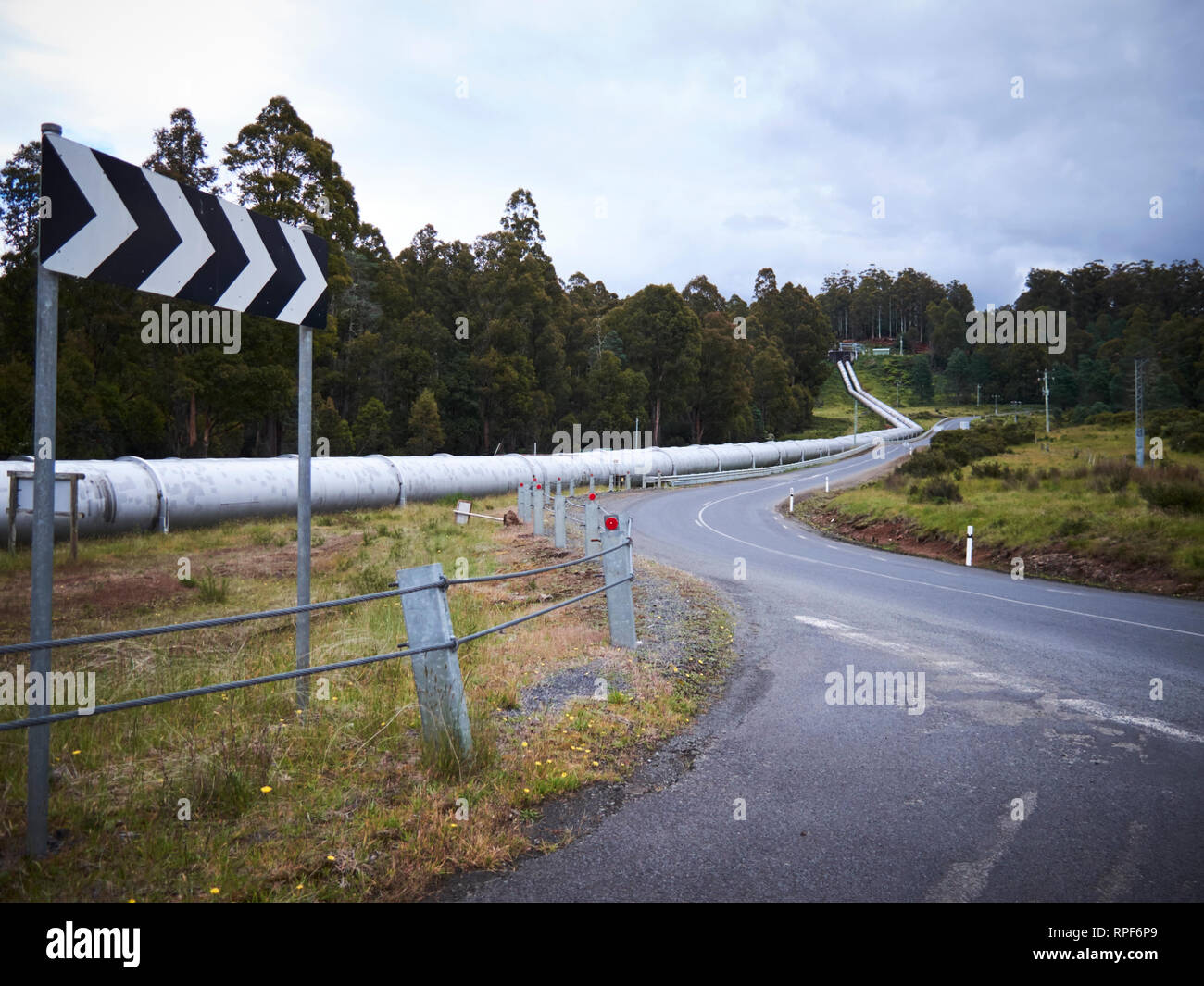 Un grand pipeline hydro irrigation suit une route sinueuse à travers la forêt campagne de Tasmanie. Banque D'Images
