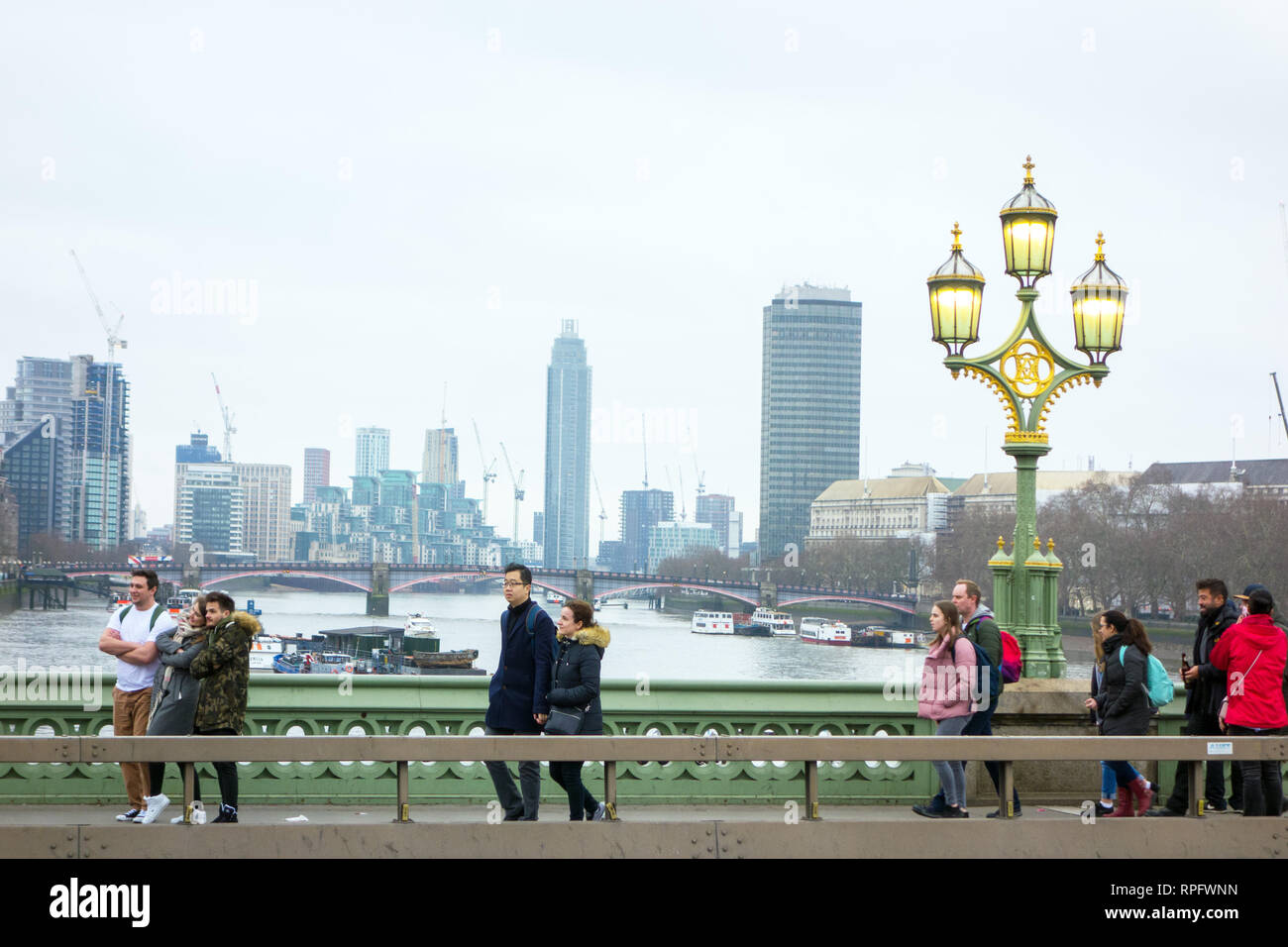 Les gens marcher sur le pont de Westminster avec tête triple lampadaire en fonte avec les lumières allumées sur la tamise Angleterre Londres Banque D'Images
