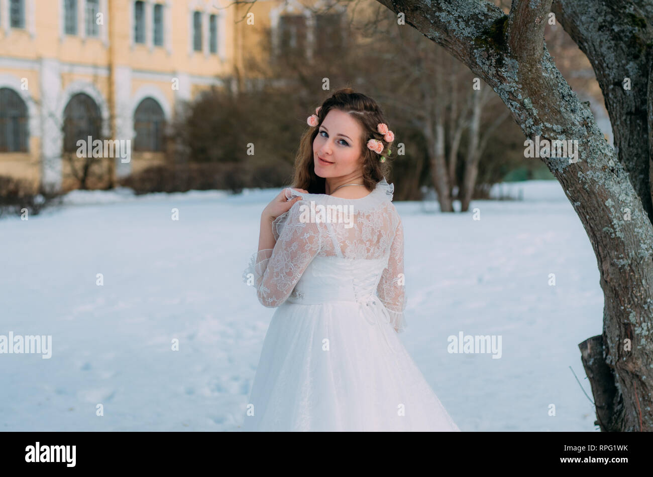 Mariée avec des roses dans les cheveux s'en retourna, l'hiver sur l'arrière-plan Banque D'Images