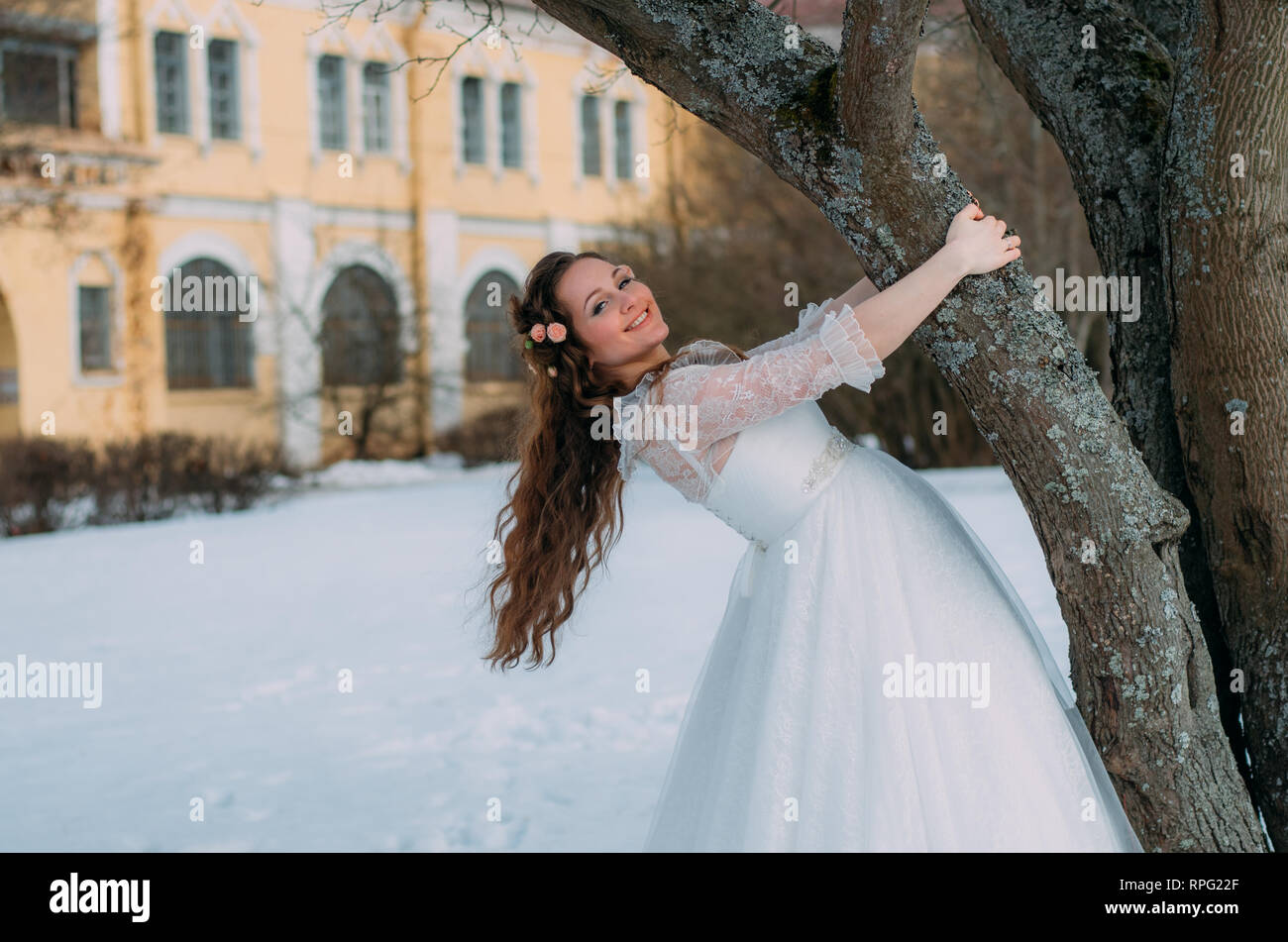 Smiling bride avec des roses dans les cheveux près de l'arbre Banque D'Images