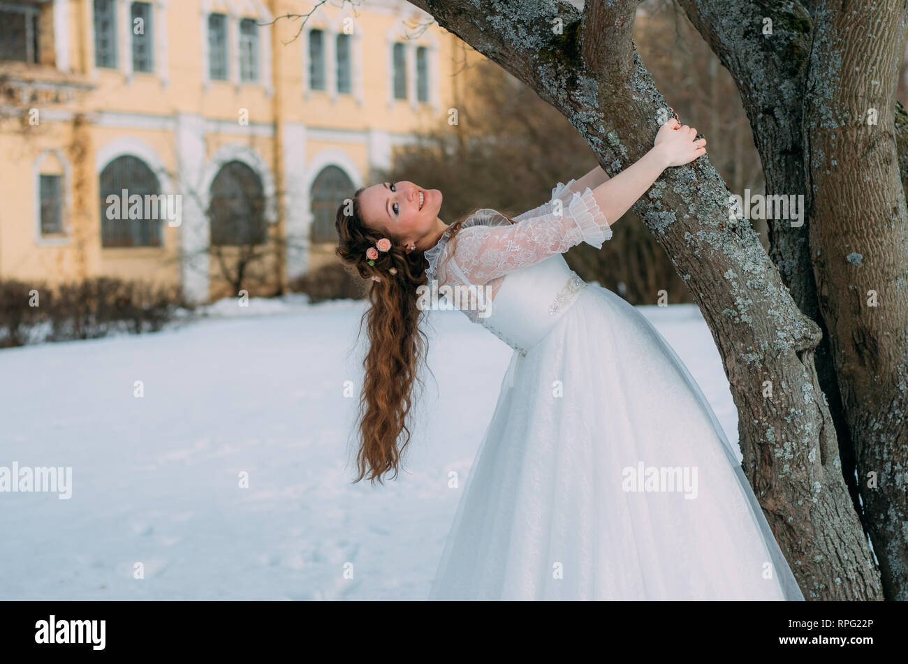 Smiling bride avec des roses dans les cheveux près de l'arbre Banque D'Images