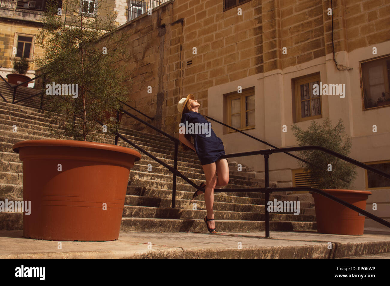 Fille assise sur les grilles de l'escalier sur la rue, vieille ville des trois villes, Malte Banque D'Images