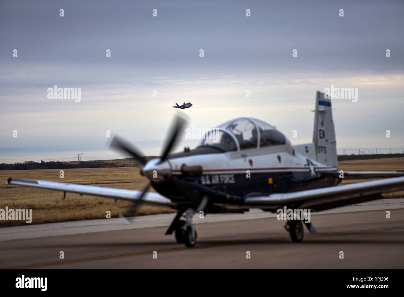 Un F-35A Lightning II à partir de la base aérienne d'Eglin, en Floride, décolle comme un T-6A Texan II les taxis en préparation pour une mission de formation à la Sheppard AFB, Texas, 10 janvier 2019. Quatre F-35 d'Eglin AFB, en Floride, s'est arrêté à Sheppard comme partie d'une base d'instruction des pilotes-étudiants road tour de montrer l'avion à la 80e Escadre d'entraînement en vol des élèves pilotes ainsi qu'en offrant la possibilité de séances d'information. Certains aviateurs d'entretien des avions F-35 en formation de la 82e Escadre de formation ont également été en mesure d'obtenir un regard étroit à la cinquième génération de chasseurs et de parler avec le service actif des aviateurs de l'entretien. (U.S. Photo de l'Armée de l'air Banque D'Images