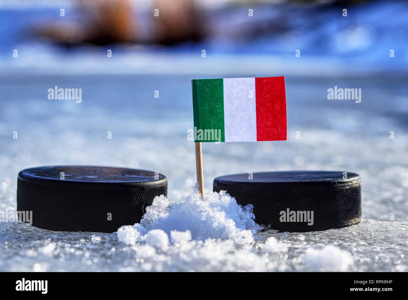 Un drapeau italien sur les cure-dents entre deux rondelles de hockey. Une Italie va jouer sur la coupe du monde en groupe B. 2019 Championnat du Monde de Hockey sur glace à Bratislava. Banque D'Images
