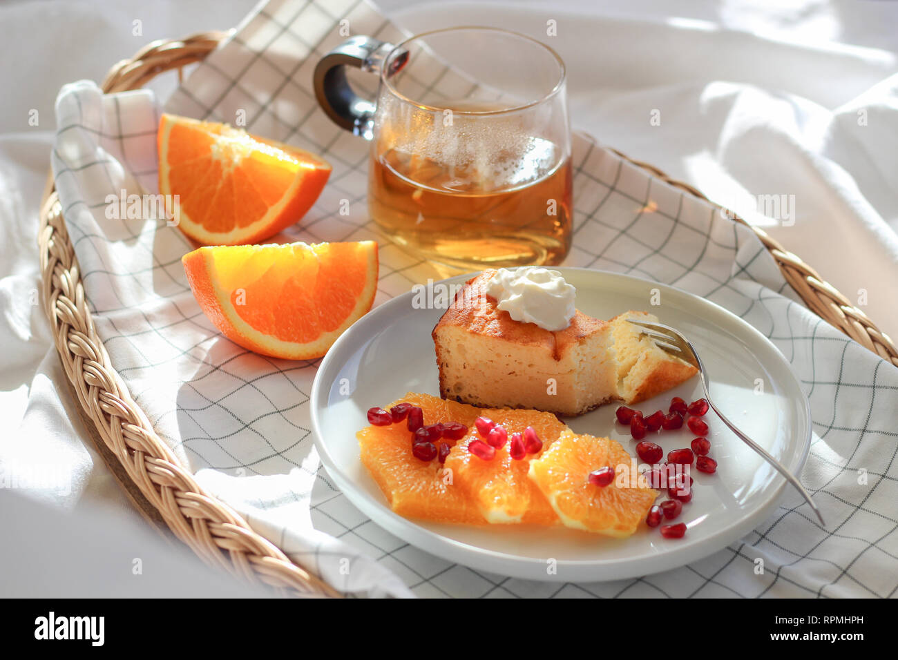 Matin dans le lit avec un morceau de gâteau et quelques tranches d'orange avec du thé sur un plateau Banque D'Images