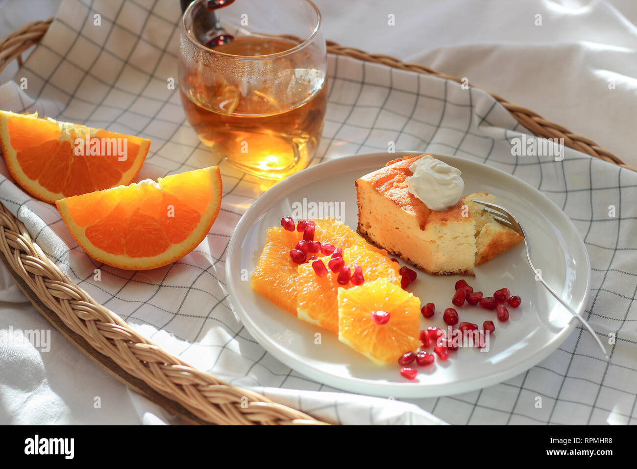 Matin dans le lit avec un morceau de gâteau et quelques tranches d'orange avec du thé sur un plateau Banque D'Images