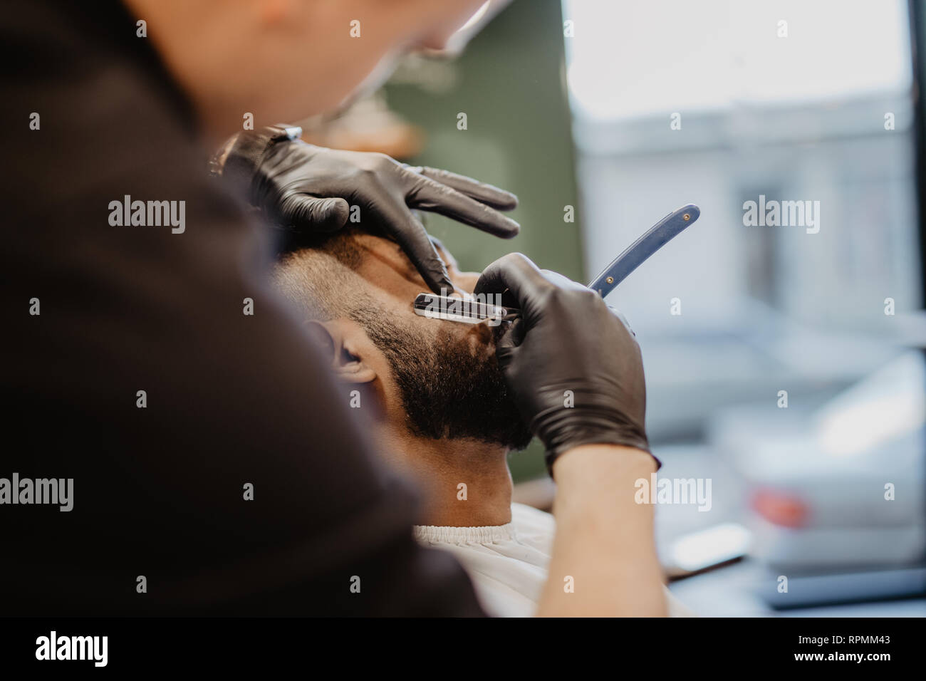 Coiffure habile. Jeune homme d'obtenir un rasage à l'ancienne avec rasoir droit Banque D'Images