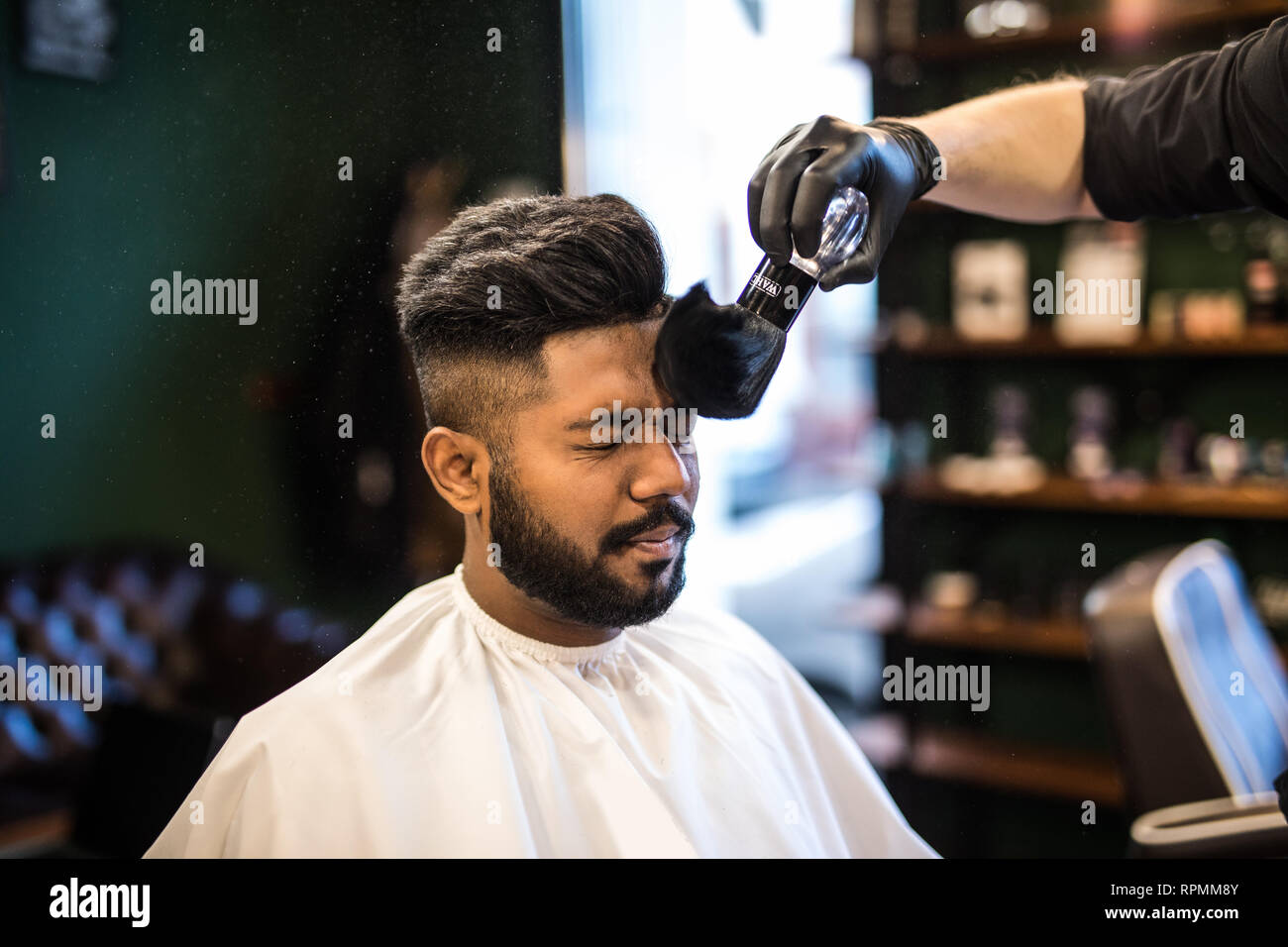 Les barbiers part propagation de la poudre de talc sur les clients professionnels avec cou blaireau en salon de coiffure pour hommes soin de beauté.concept.jeune homme noir ge Banque D'Images
