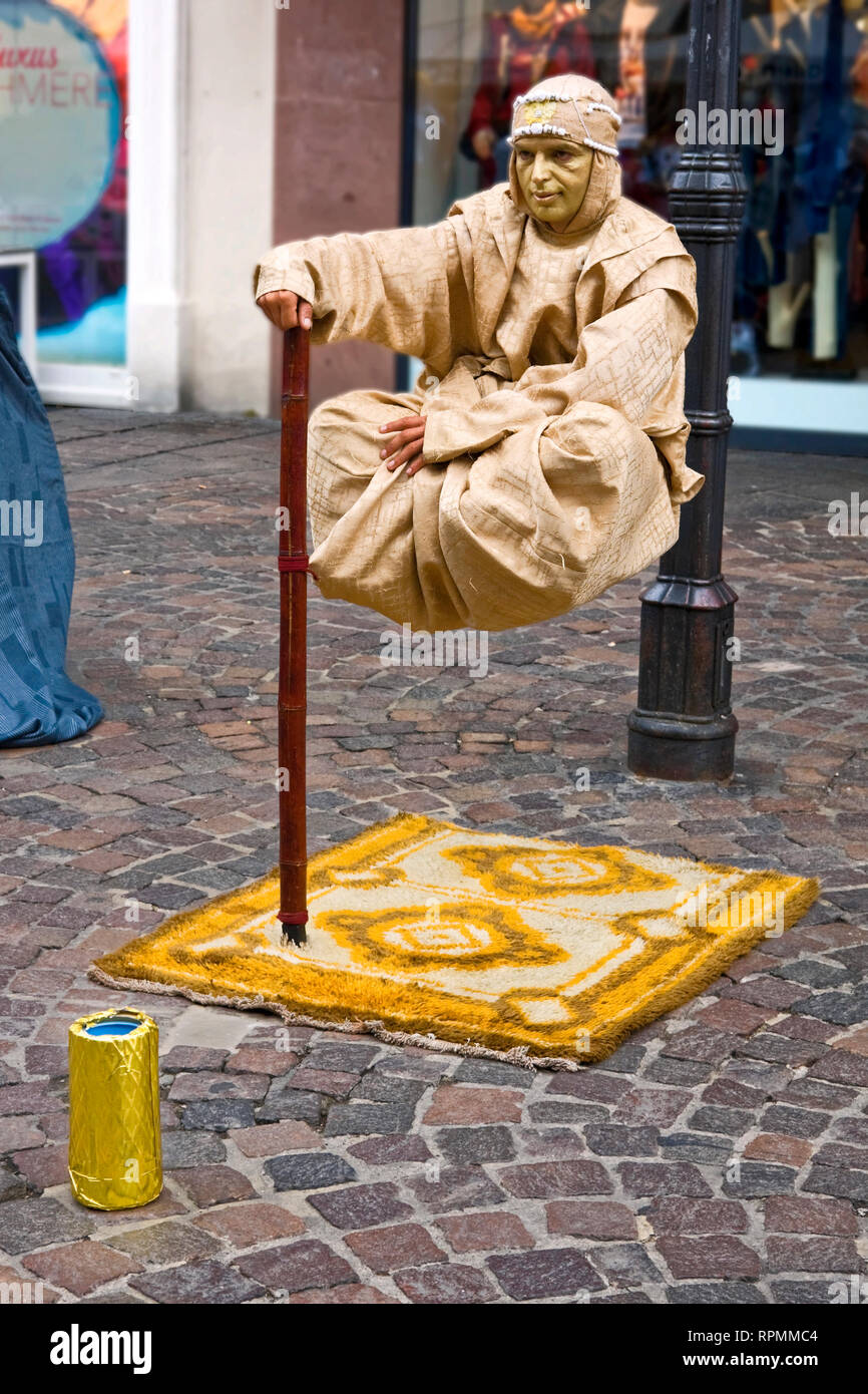 Homme mime, suspendu au-dessus de trottoir, tapis, face à l'or, intelligent ; gagner de l'argent ; travail, imagination, rue commerçante ; juge ; Allemagne ; vertical Banque D'Images