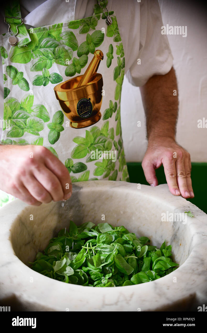 Un close-up de Roberto Panizza's hands l'addition de sel à certains frais haché basilic Pesto génois de bien faire à son restaurant à Gênes, Italie Banque D'Images