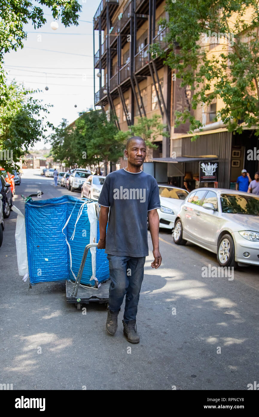 Johannesburg, Afrique du Sud, 19 octobre -2018 : foutaise picker marche avec des matériaux recyclables dans un grand sac. Banque D'Images