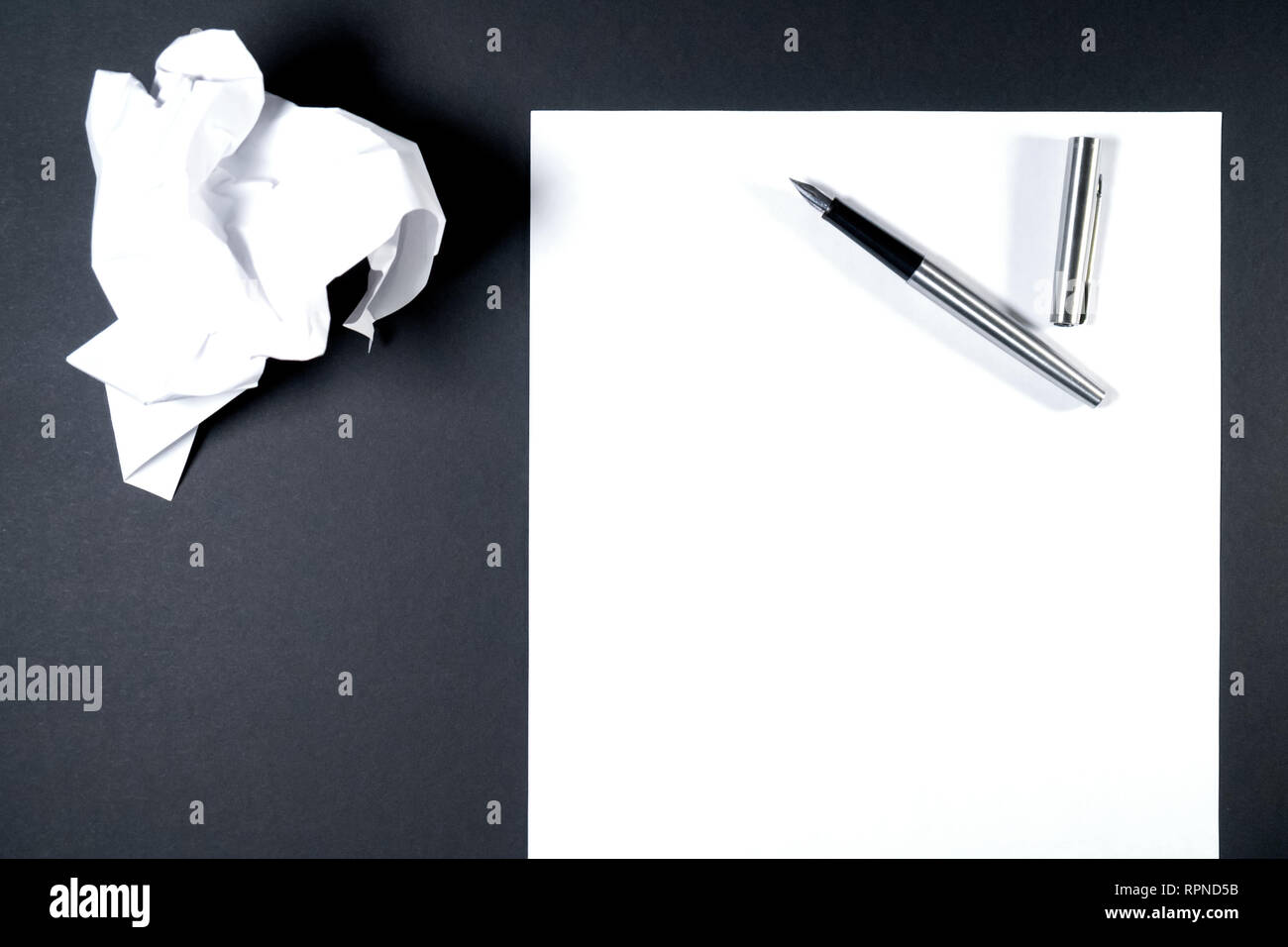 Sur une feuille de papier est un stylo d'encre, à côté d'une feuille froissée. Fond noir Banque D'Images