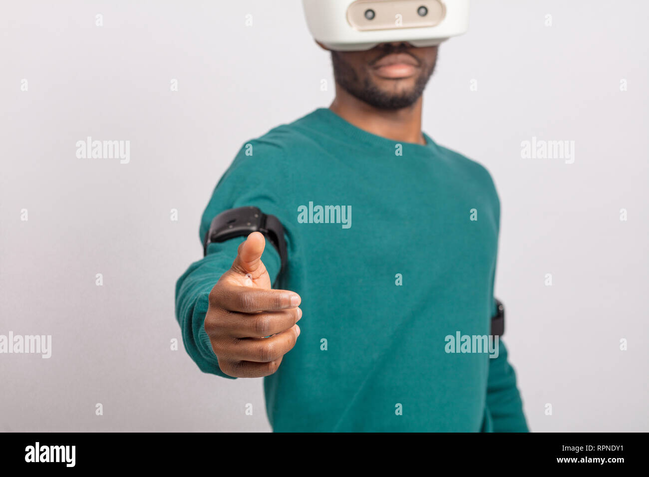 Guy africains en vert poolover de réalité virtuelle en 3d à l'aide de casque pour téléphone intelligent, en tendant la main avec open palm comme si nous invitant à j Banque D'Images