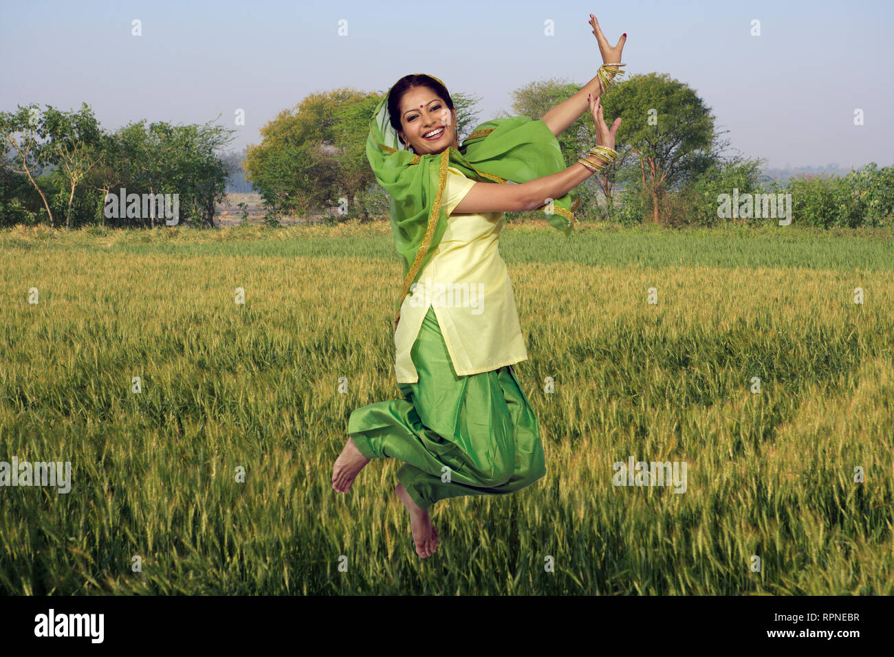 PORTRAIT D'UNE FEMME SIKH, SARDANI DANSE BHANGRA LE SAUT AVEC DES CHAMPS DE BLÉ DANS L'ARRIÈRE-PLAN Banque D'Images