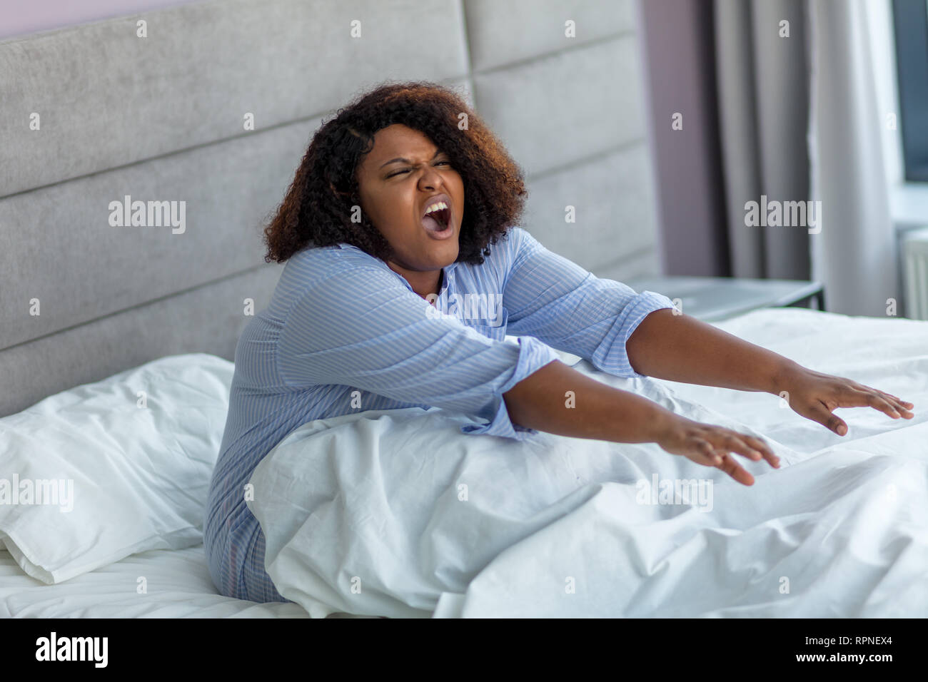 Lazy grosse fille assis dans le lit. La photo en gros. nouvelle journée, la  paresse, femme au foyer africain avec bouche ouverte qui s'étend dans le lit  Photo Stock - Alamy