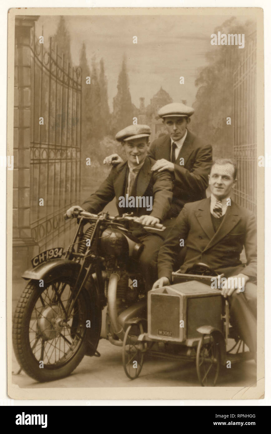 Carte postale originale des années 1930 pour le portrait de studio d'hommes heureux portant des costumes et des casquettes plates, posant sur un prop de moto, profitant de leurs vacances annuelles ou de leur départ, datée du 20 octobre 1934, Blackpool, Lancashire, Royaume-Uni Banque D'Images