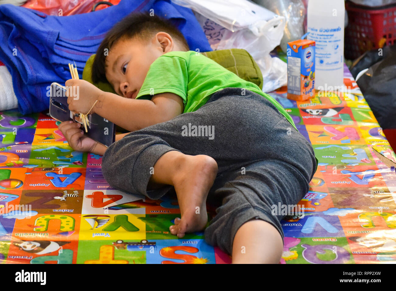 Enfant jouant à des jeux sur un téléphone, Chiang Mai Banque D'Images