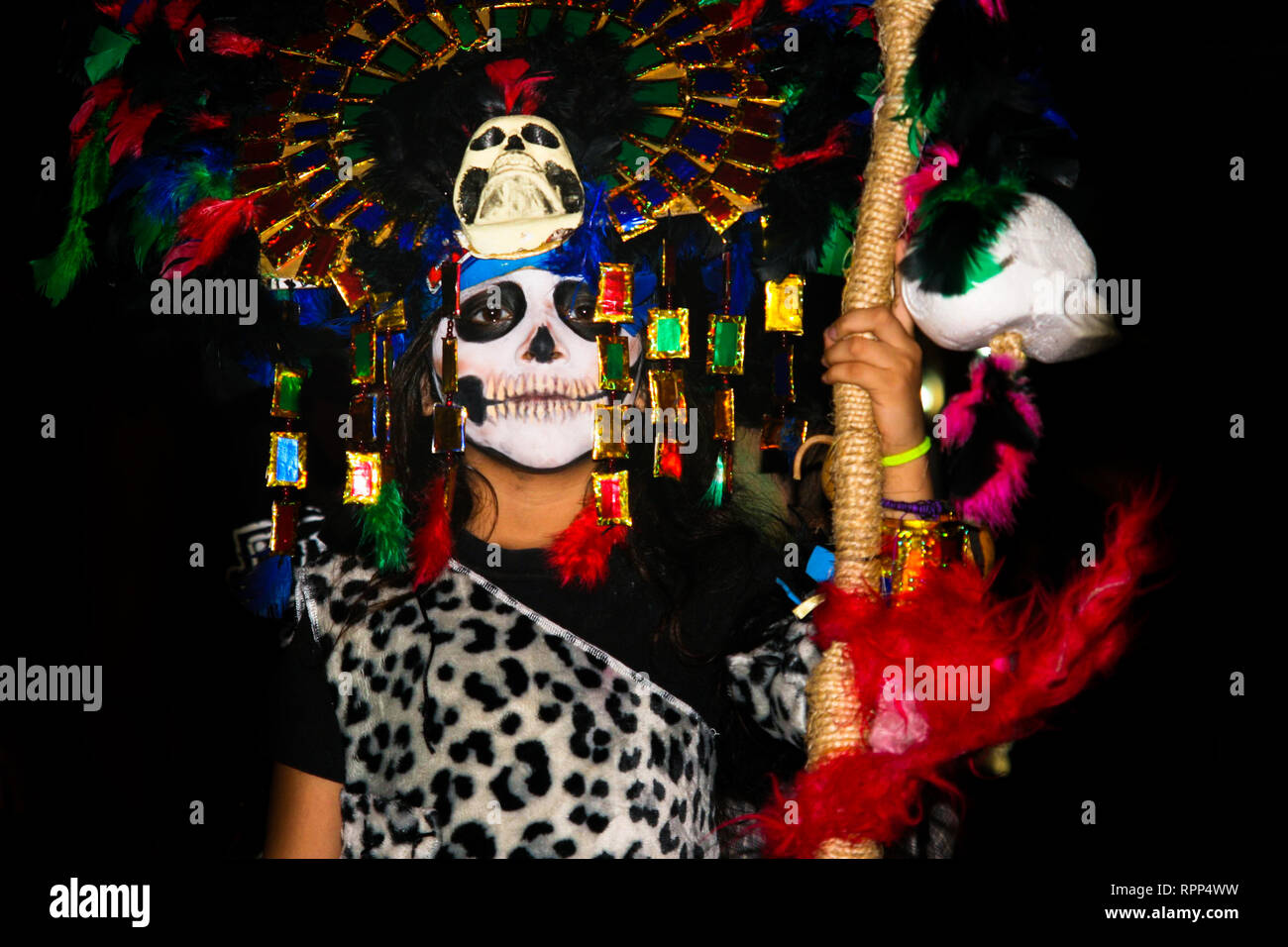 Portrait d'enfant déguisé, avec beaucoup de plumes colorées et masque de crâne maya, le port de tenue léopard, debout dans la rue au cours de l'Assemblée mexicas Banque D'Images