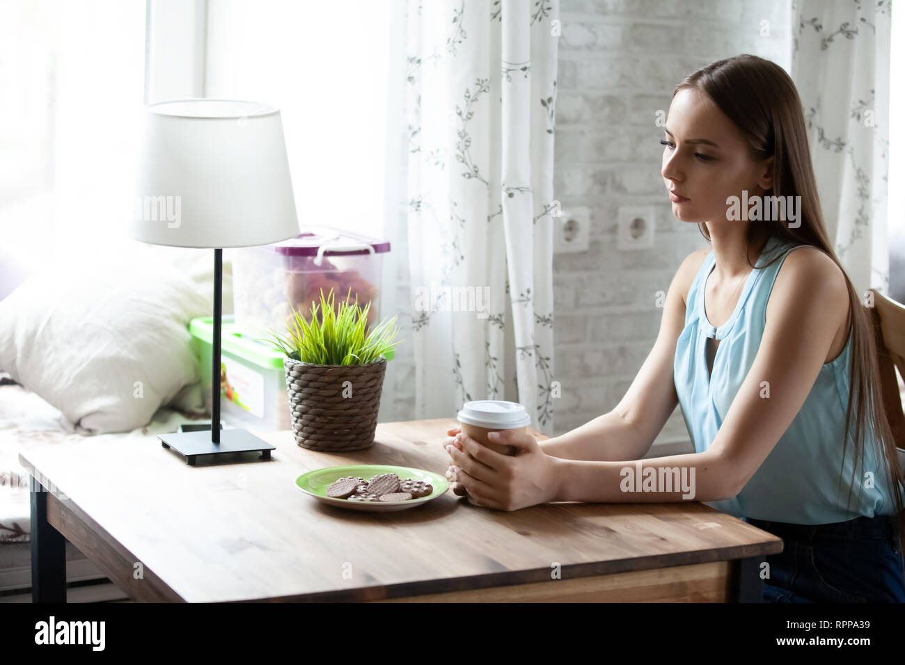 Jeune femme seule assise à table et de boire du café en café Banque D'Images