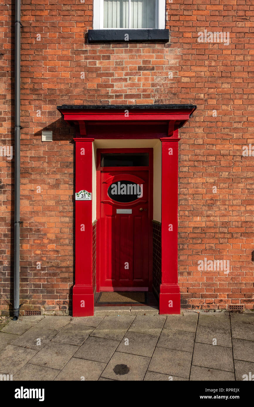Gros plan du 1950 - 1960 Red porte avant avec fenêtre ovale et porche sur une maison de briques rouges en marché, Tickhill dans la région métropolitaine de Don Banque D'Images