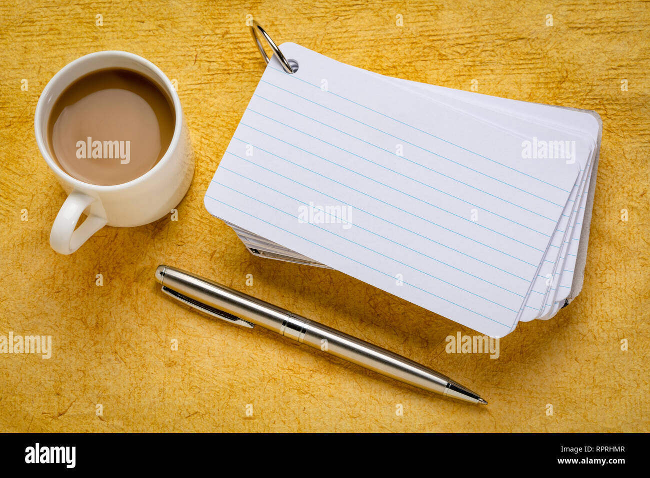 Pile de fiches vierges avec une tasse de café et un stylo contre le papier texturé jaune Banque D'Images