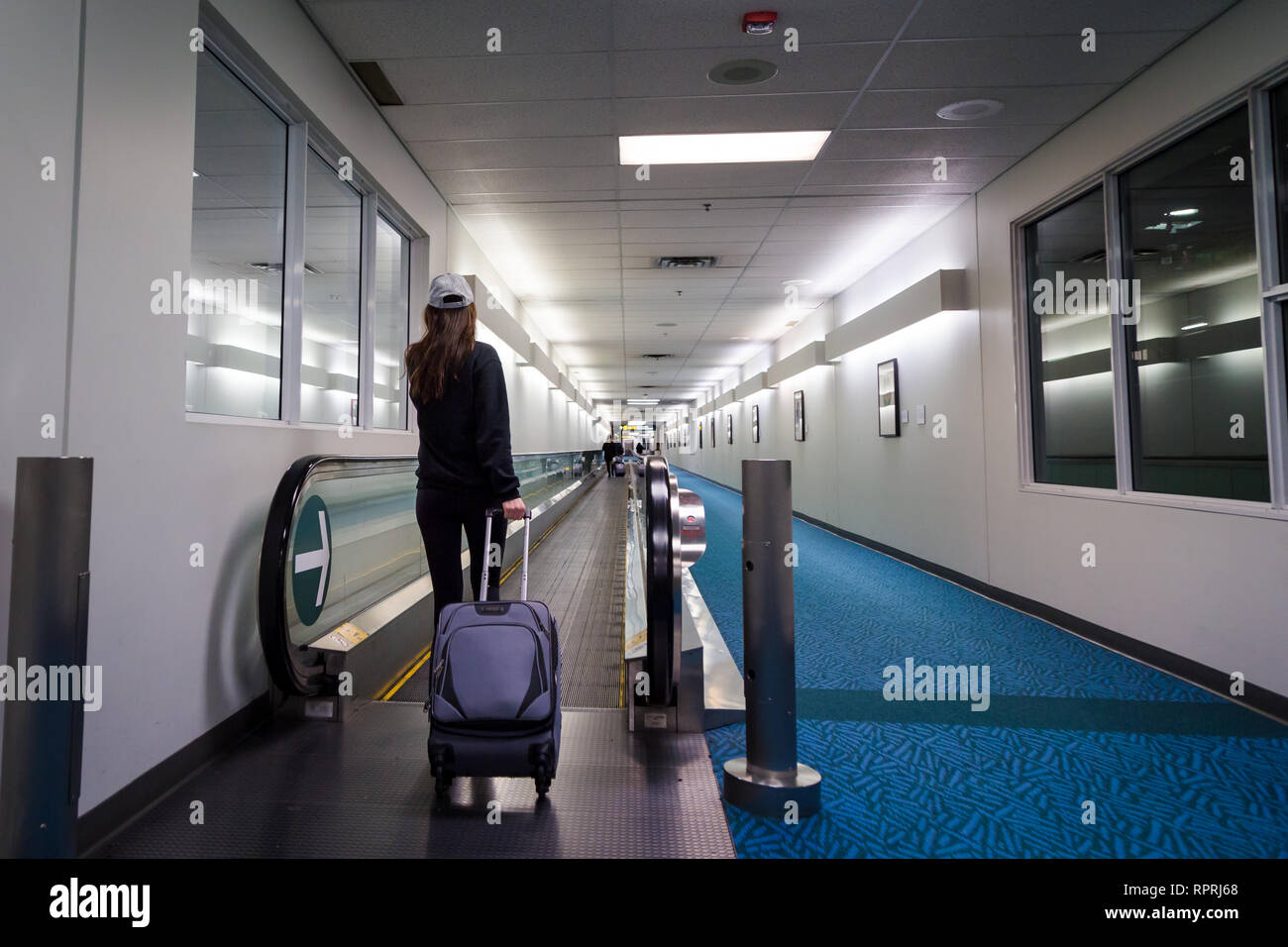 Jeune femme brune avec ses bagages dans un hall de l'aéroport. Banque D'Images