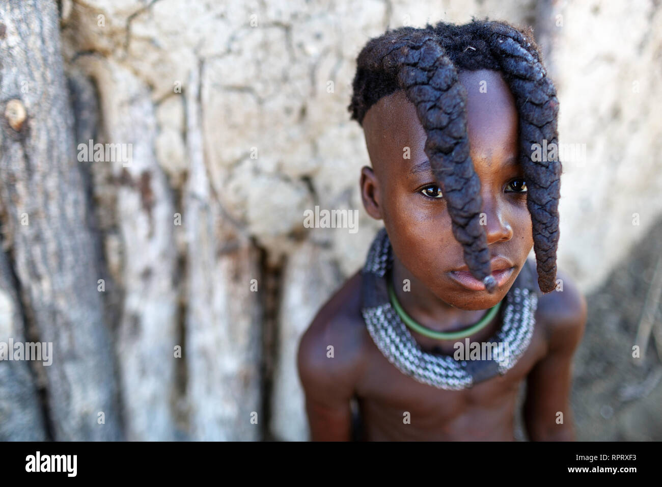 Jeune fille Himba avec deux tresses et des bijoux, portrait, Himba hut, Himba village, le nord de la Namibie Banque D'Images