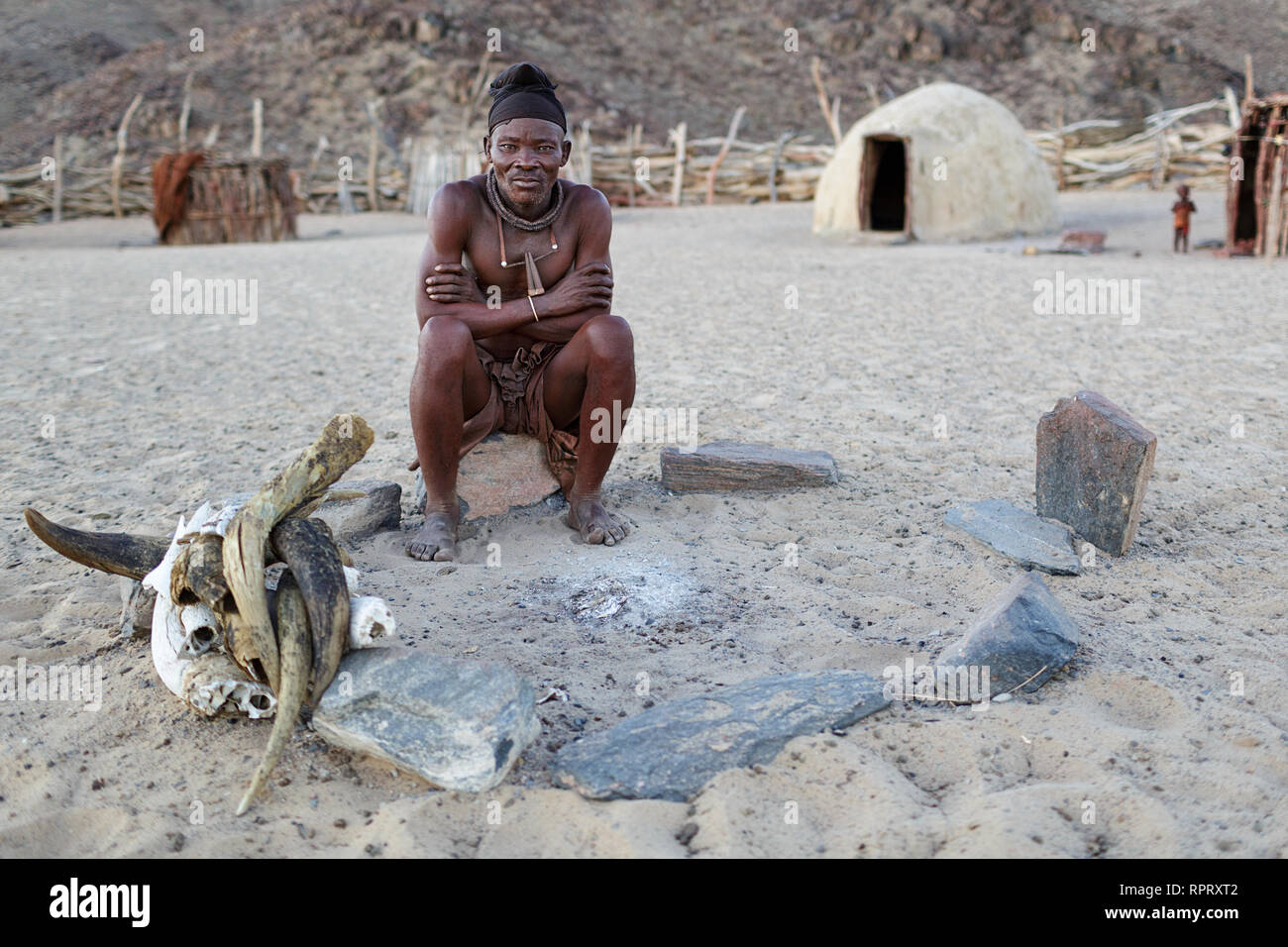 Le chef du village Himba assis par cheminée, Purros, Namibie Banque D'Images