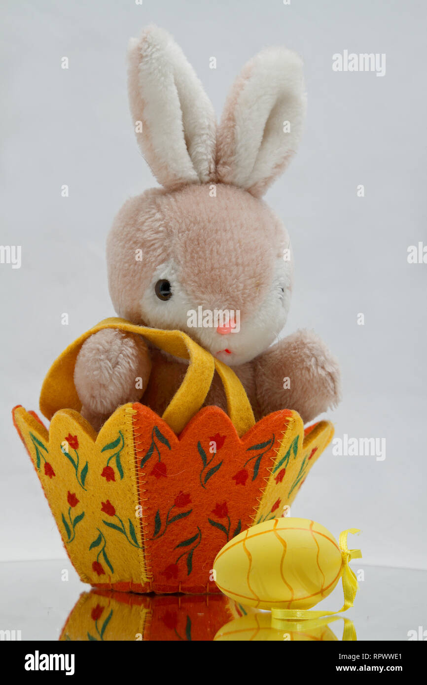 Une peluche bunny assis dans un panier de Pâques et des oeufs de pâques avec Banque D'Images