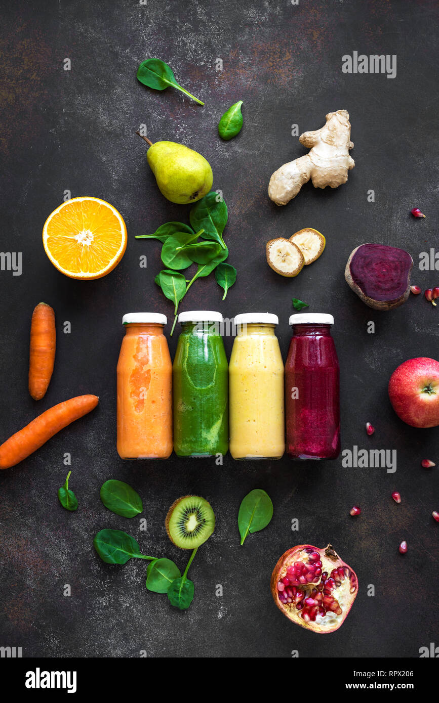 Divers smoothies colorés ou de jus dans des bouteilles et des ingrédients sur l'obscurité. Régime alimentaire sain detox nettoyer vegan food concept, vue du dessus. Banque D'Images