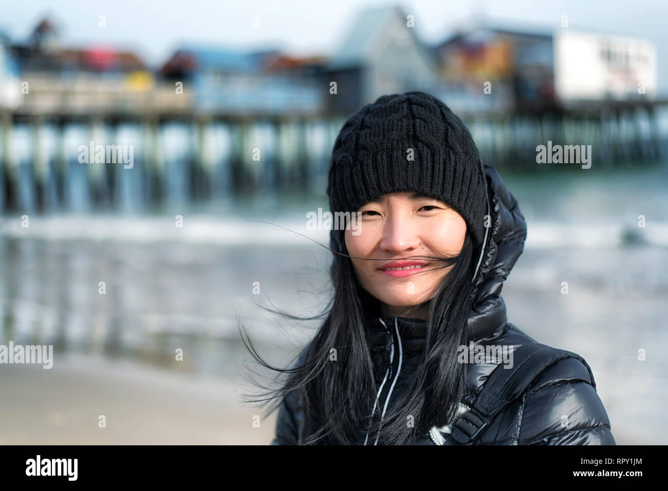 Une femme chinoise portant une veste d'hiver dans le vent soufflant à Old Orchard Beach dans le Maine sur une journée ensoleillée. Banque D'Images