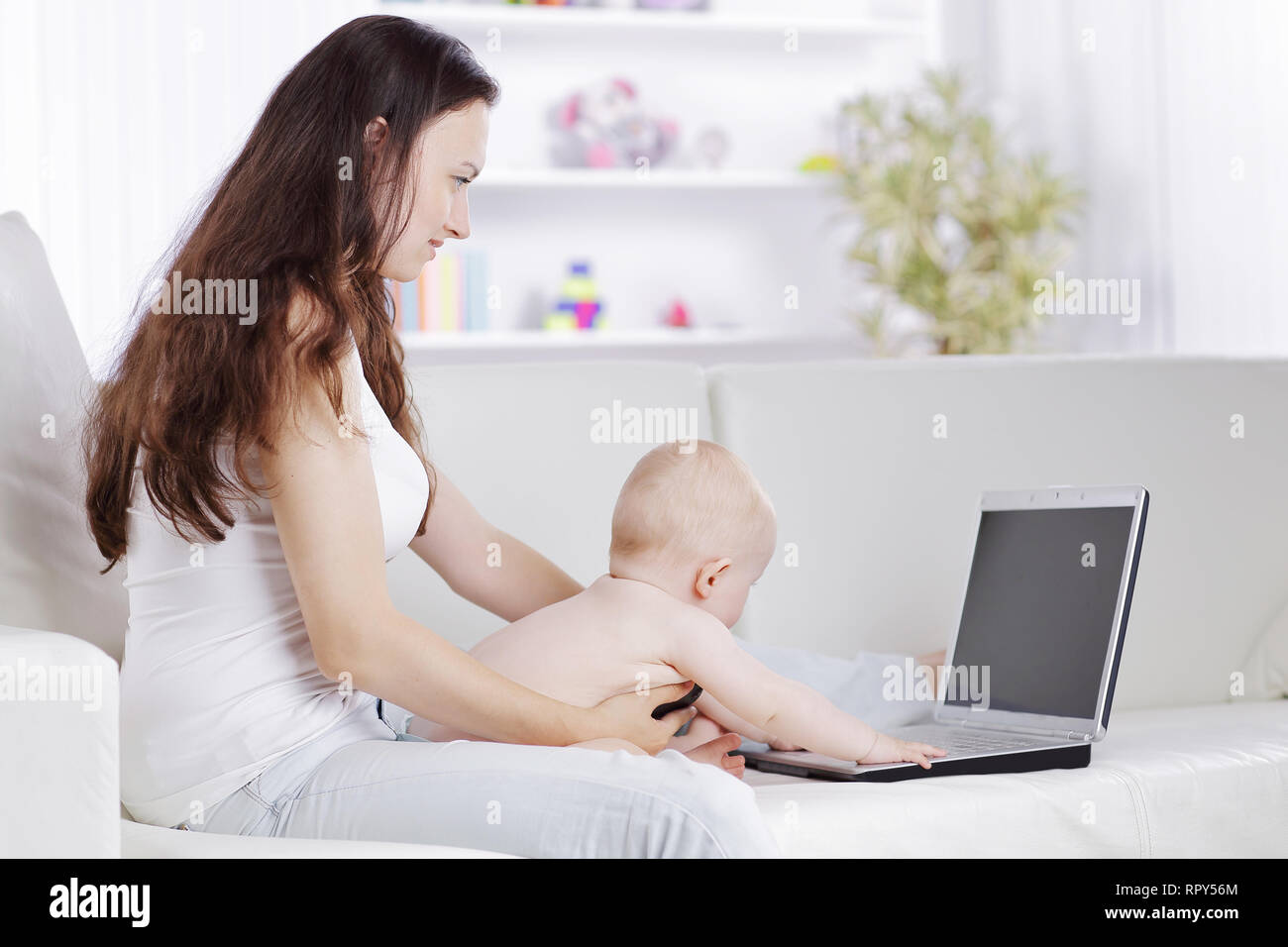 Jeune mère joue avec le bébé et parler sur un téléphone mobile Banque D'Images