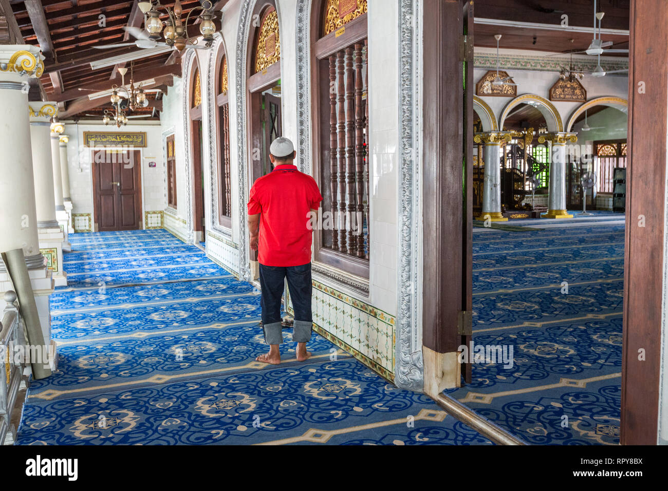 Adorateur de prier dans couloir à l'extérieur grande salle de prière de Kampung Kling Mosquée, Masjid Kampung Kling, Melaka, Malaisie. Banque D'Images