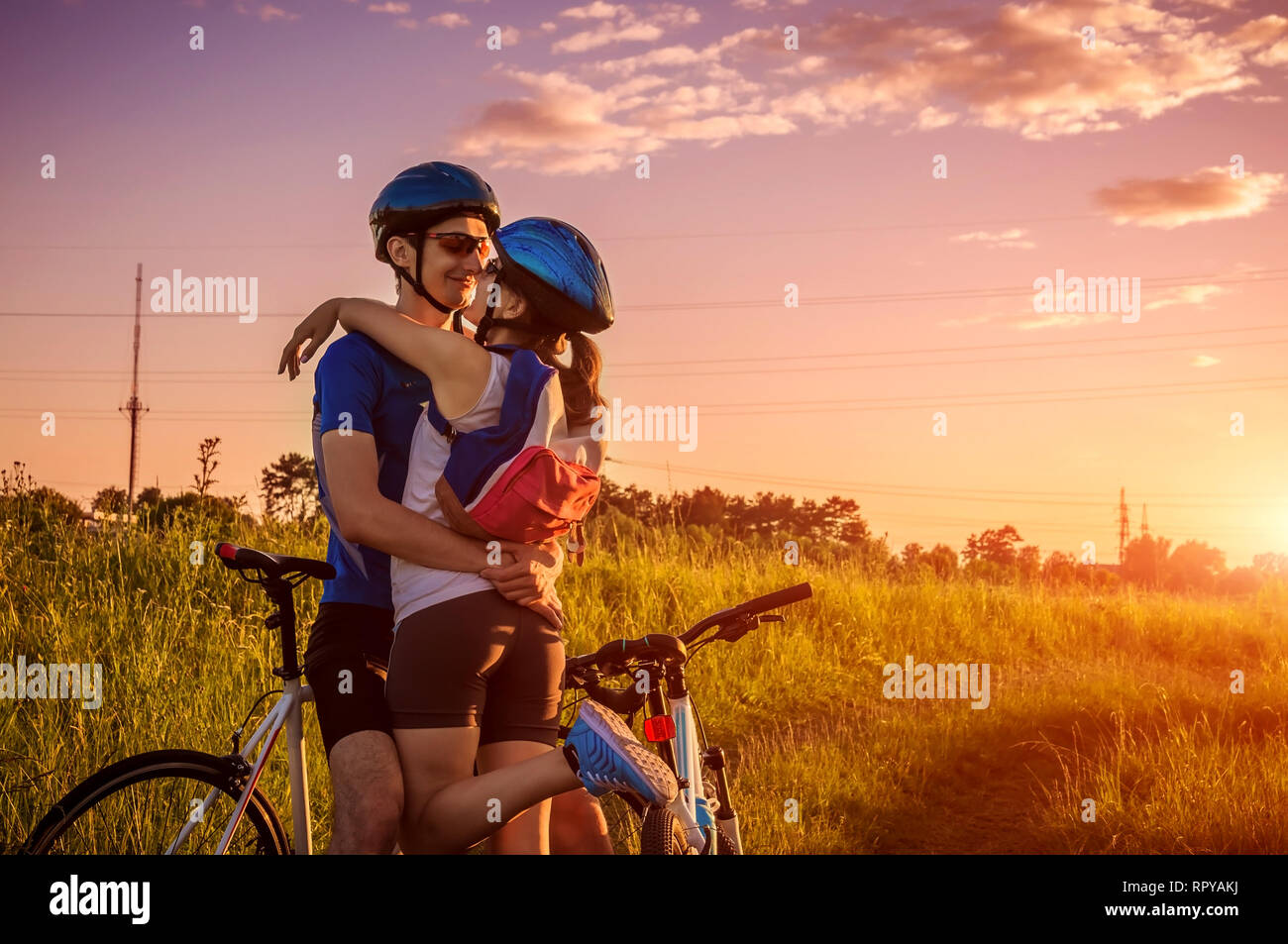 Couple de cyclistes hugging après l'équitation dans les banlieues au coucher du soleil. Vie saine et active. Les jeunes vététistes voyager ensemble Banque D'Images