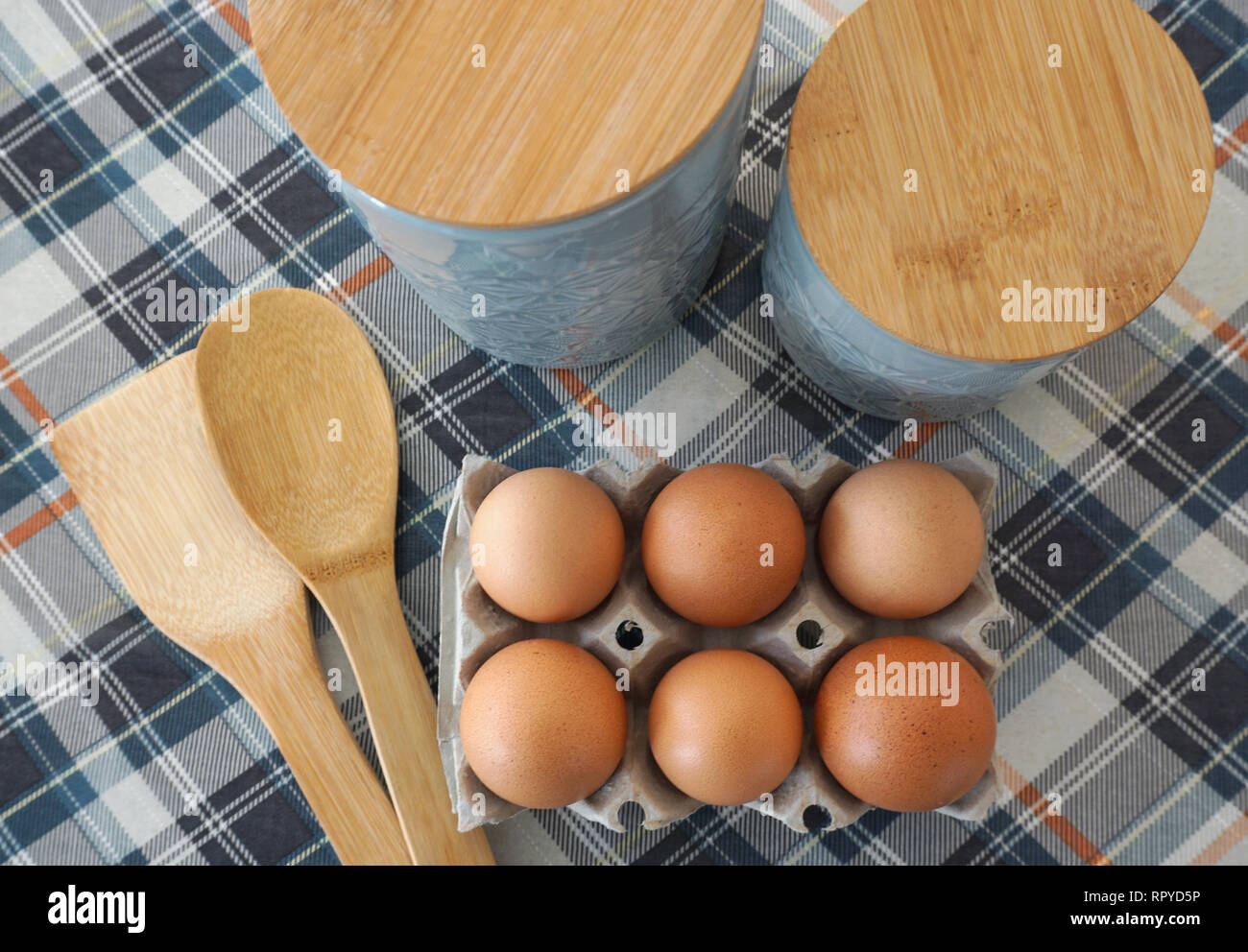 Six oeufs crus dans un emballage en carton sur la table de cuisine Vue de dessus, avec une cuillère de bois et de nourriture contenant cuisine vue du dessus. Concept de cuisson Banque D'Images