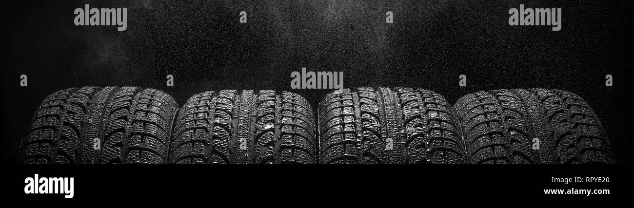 Quatre pneus d'affilée avec de l'eau gouttes sur fond noir, copyspace pour votre texte ou photo horizontale concept publicitaire studio shot, personne ne Banque D'Images