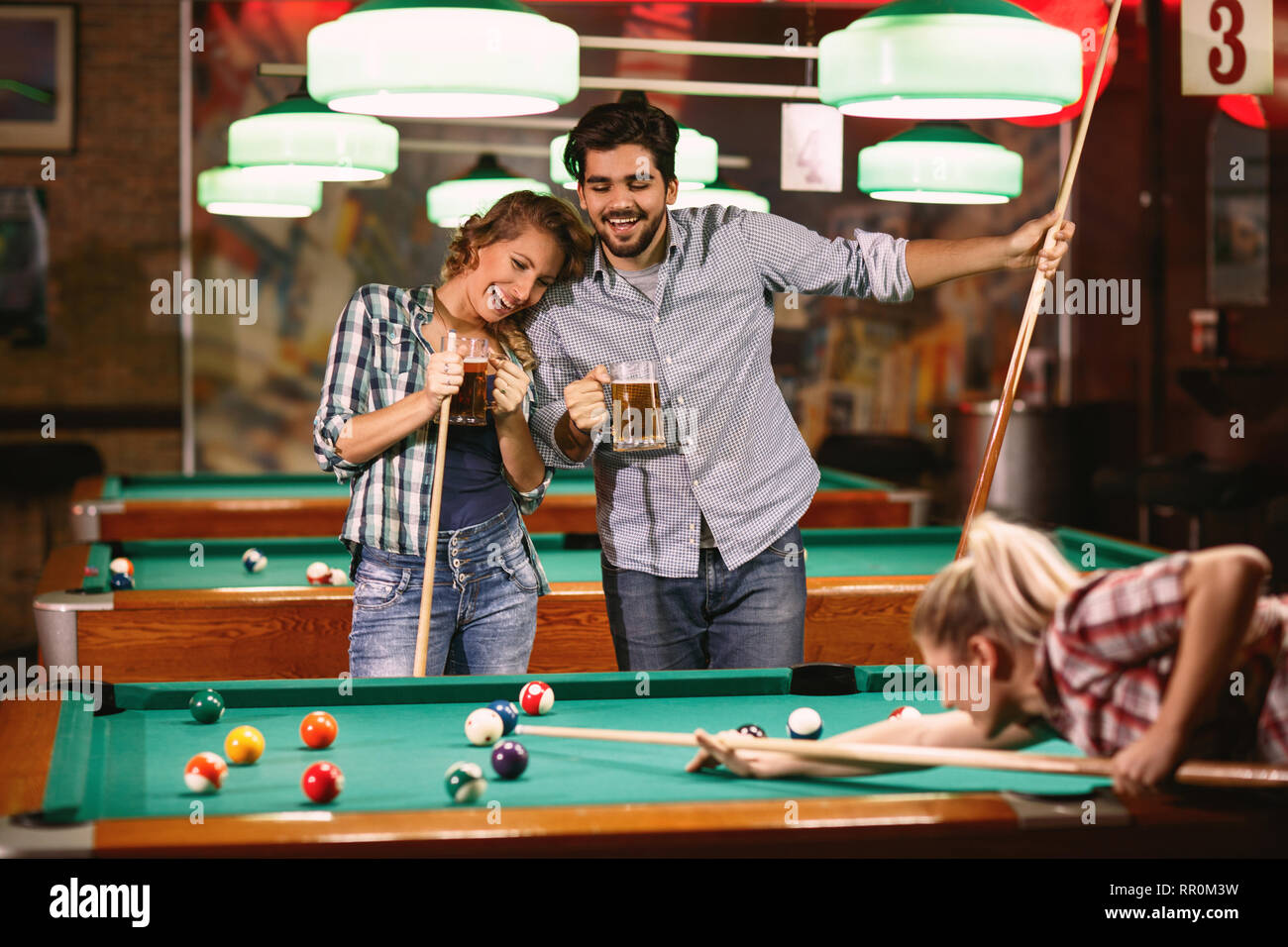 Smiling friends playing snooker billard ou Banque D'Images