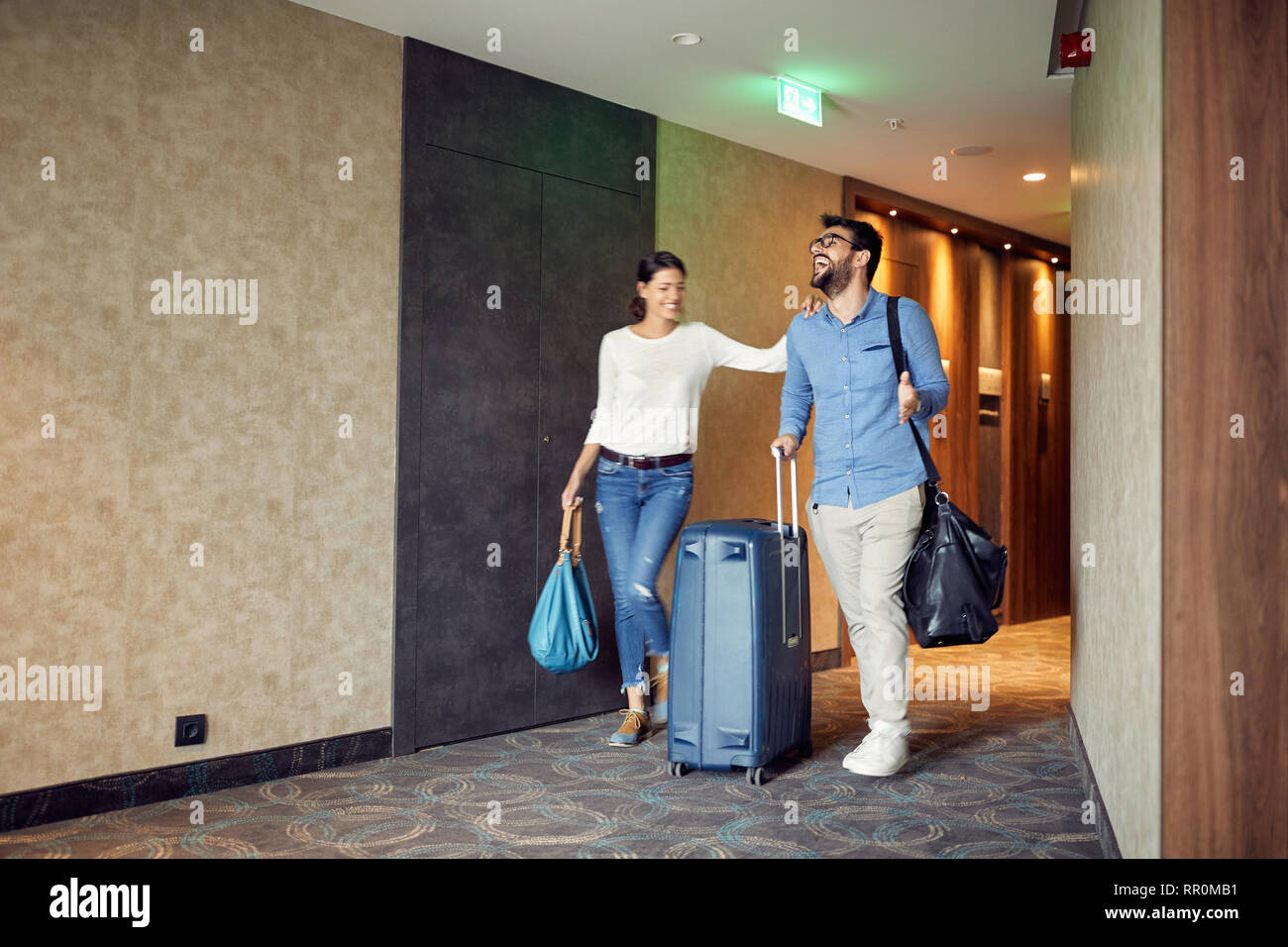 Heureux l'homme et la femme d'arriver à l'hôtel lobby avec valise de appartement Banque D'Images