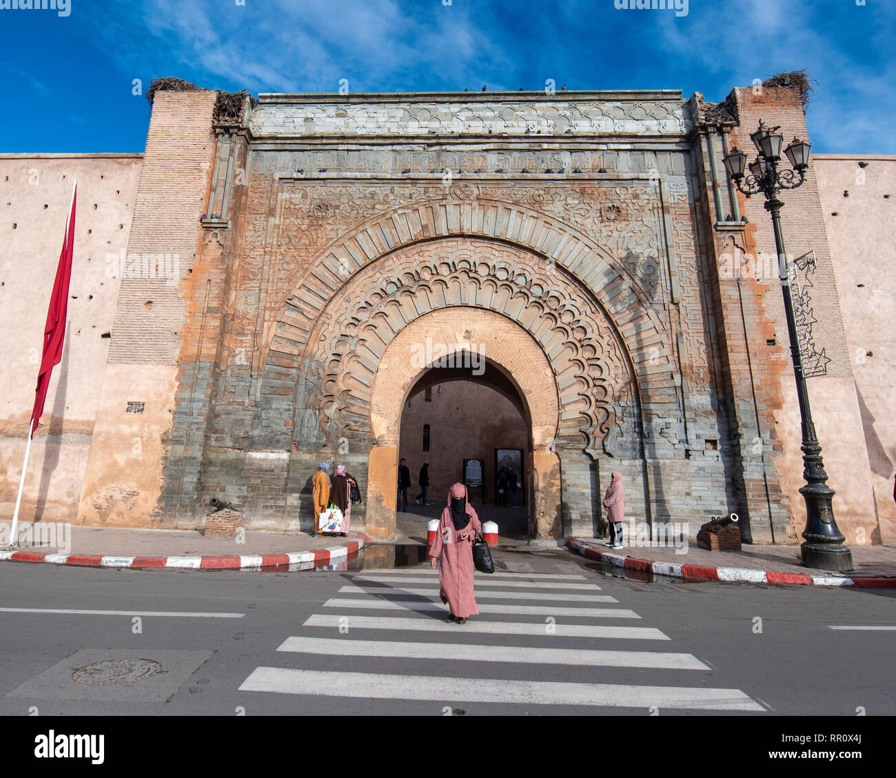 Femme arabe traverser un chemin piéton en face de la porte Bab Agnaou Ville . Entrée de la vieille ville - la médina de Marrakech, Maroc Banque D'Images