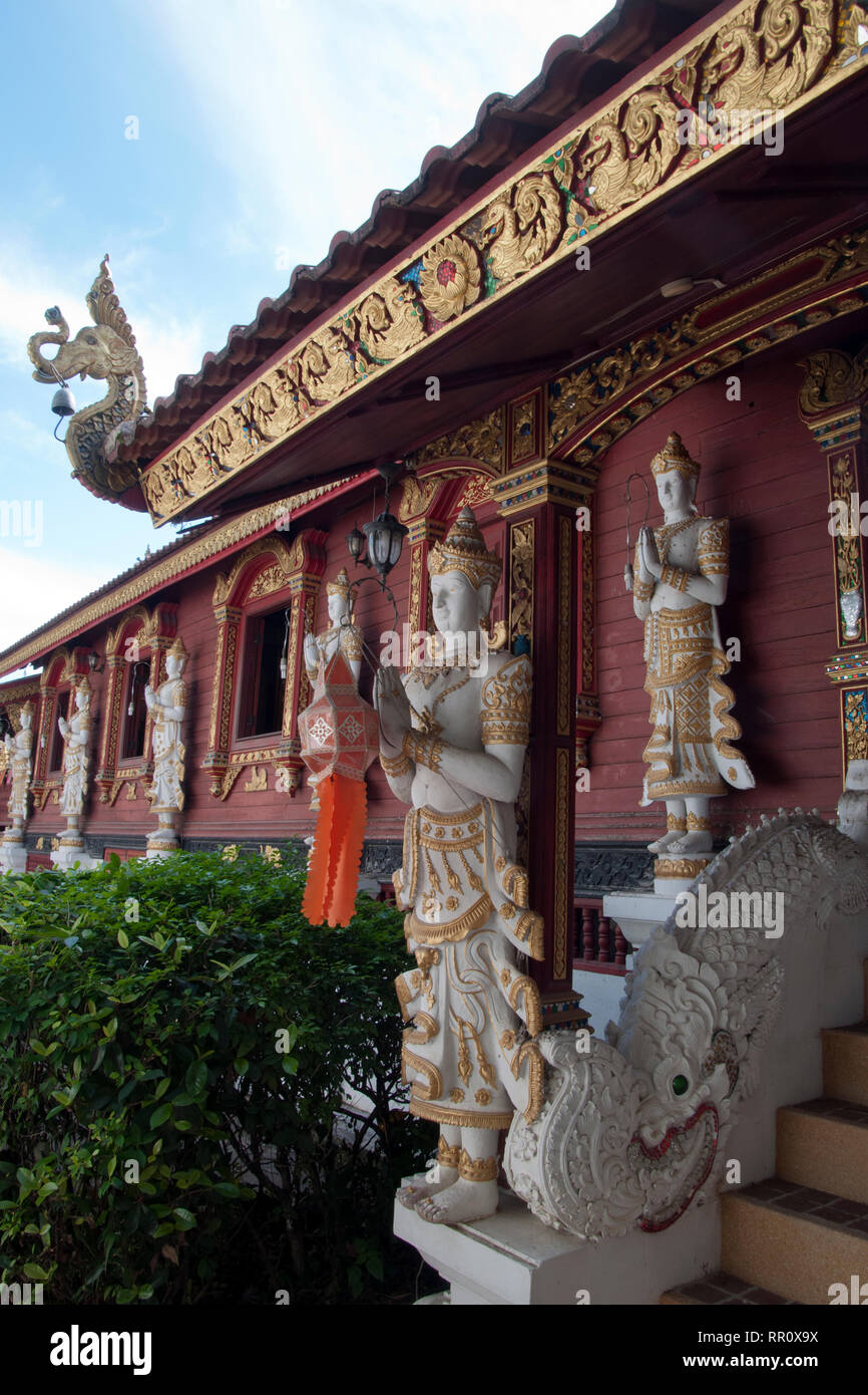 Chiang Rai en Thaïlande, statues tenant dans mur rouge à Wat Ming Muang Banque D'Images