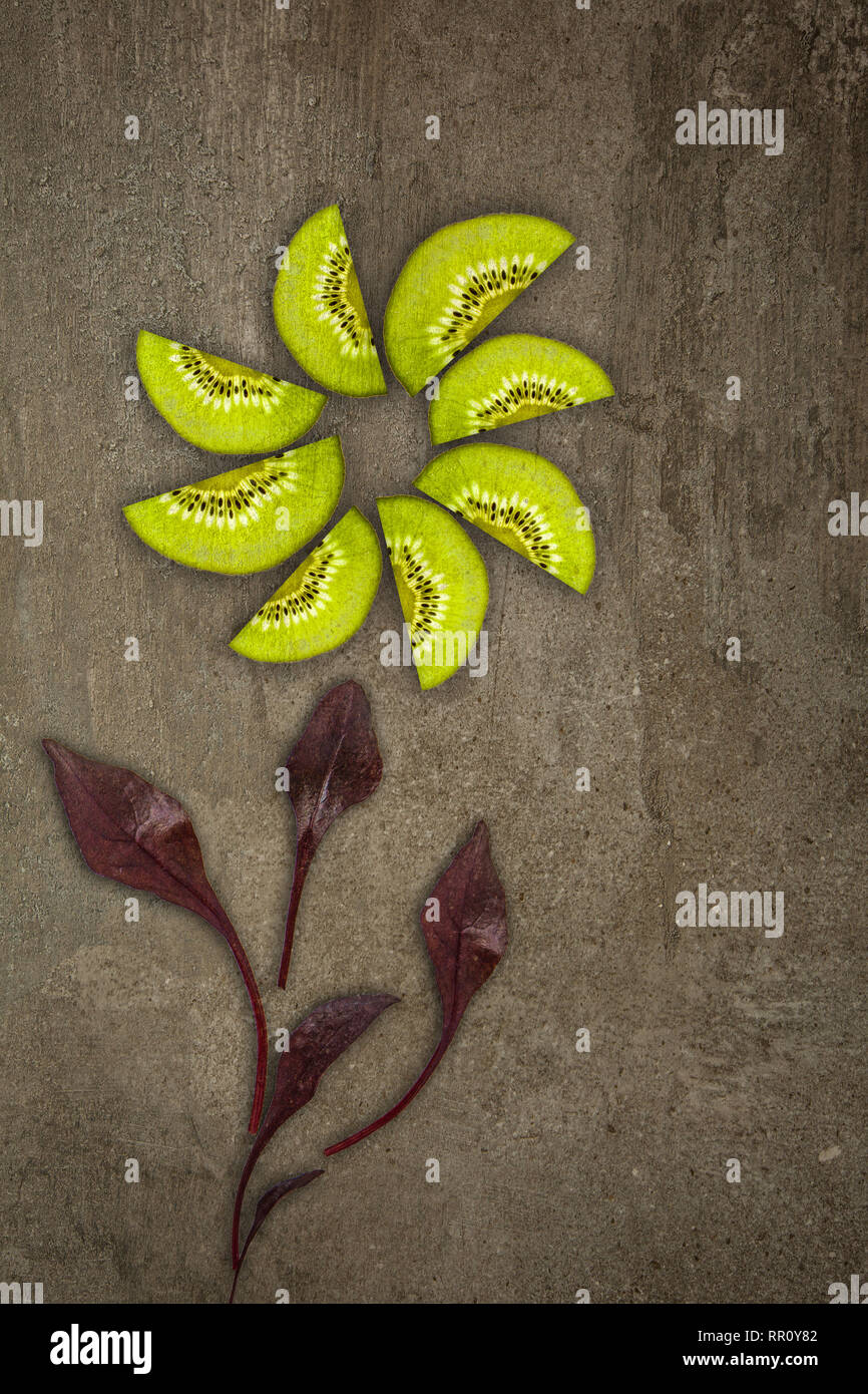 Fleur Créatif fait de kiwis avec betterave feuilles coupées à partir de ci-dessous allumé sur un fond de pierre concept alimentaire Banque D'Images