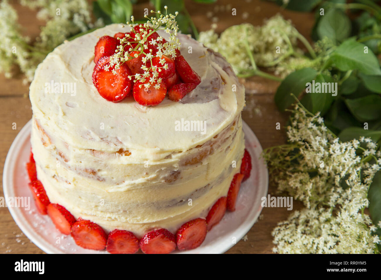 Gâteau avec une crème de chocolat blanc et fraises avec frère on wooden table Banque D'Images