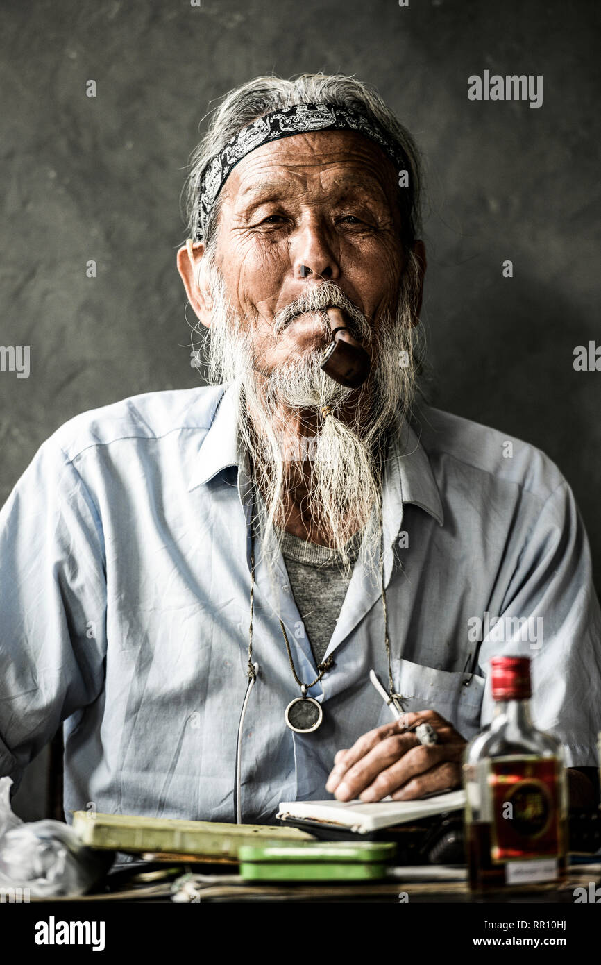 Portrait d'un vieil homme japonais fumant une pipe tandis que sur la table il y a une bouteille de rhum et de peinture. Osaka, Japon. Banque D'Images