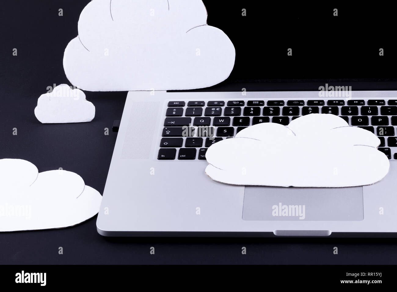 Le concept de cloud computing avec les nuages au-dessus d'un clavier d'ordinateur portable sur un fond noir Banque D'Images
