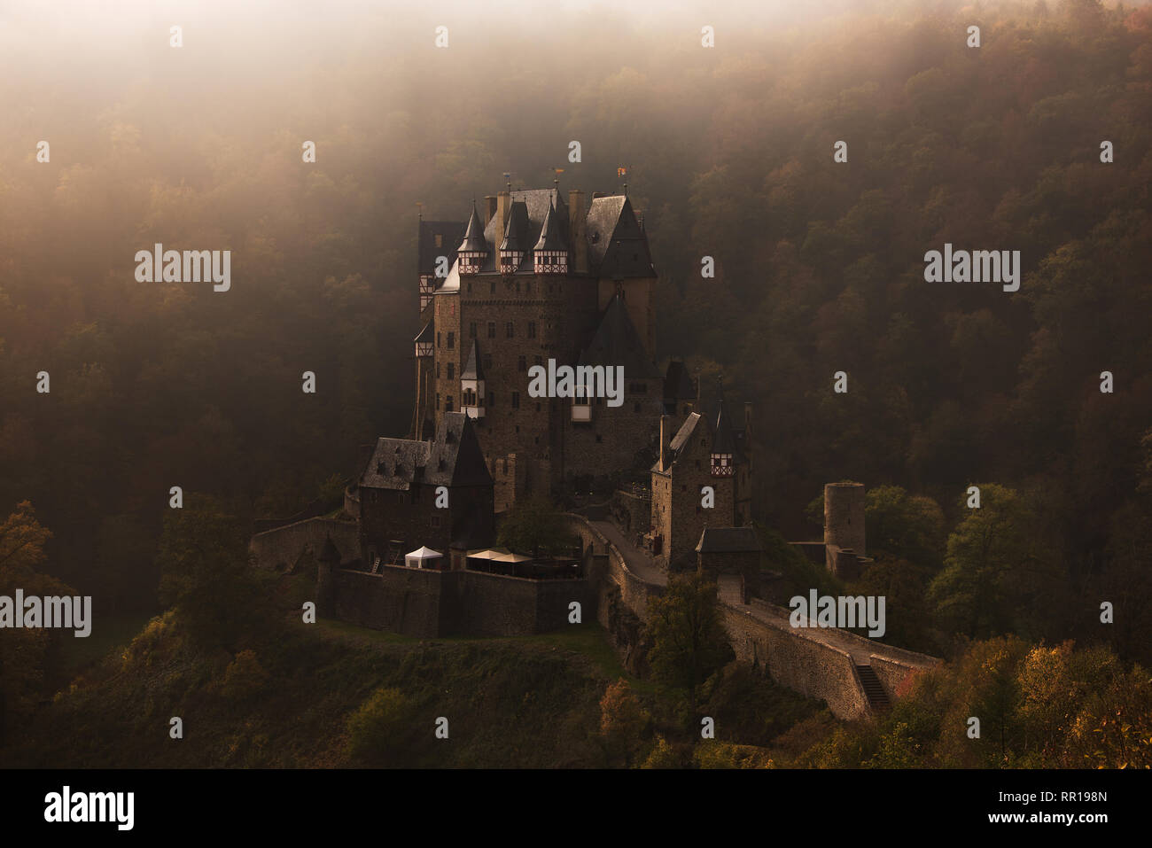 La cité médiévale château Burg Eltz, construit sur un rocher dans une forêt en automne couleurs entouré par le brouillard du matin près de la Moselle en Allemagne, Wierschem. Banque D'Images